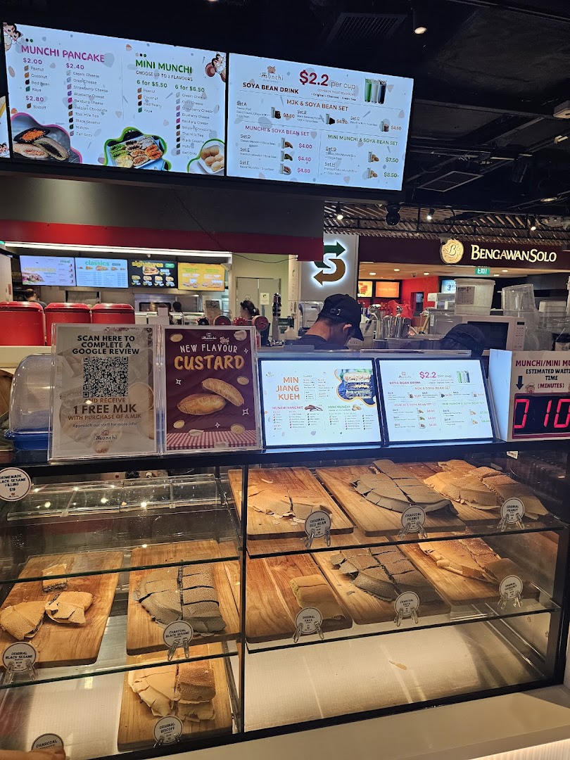 Digital menu boards and a display counter showcasing various pancakes and drinks at Munchi Pancakes.