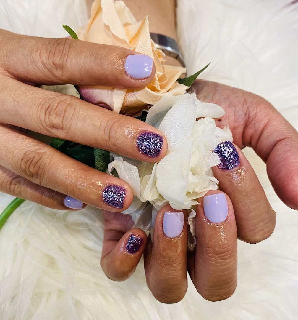 Close-up of hands showcasing a fresh manicure with purple glitter and lavender nail polish.