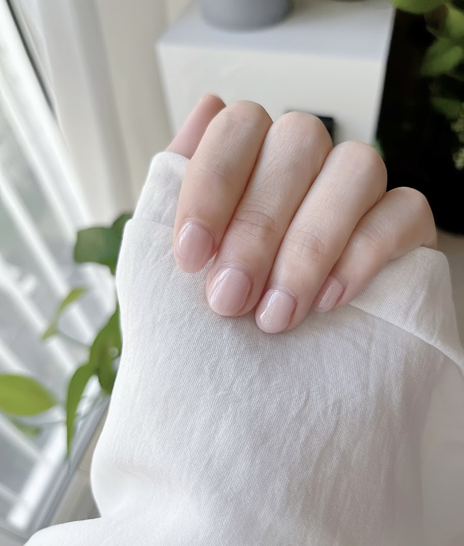 A hand showcasing a fresh, natural-looking manicure with a subtle, glossy finish.