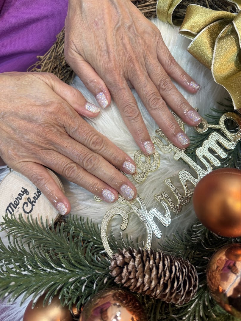 Close-up of hands with sparkling glitter nails amidst festive Christmas decorations, showcasing a manicure.
