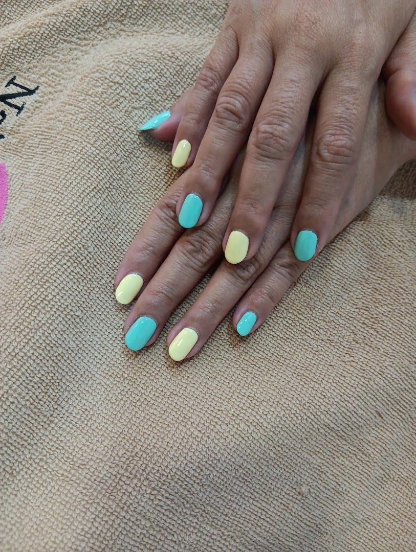 A close-up of hands with freshly painted nails in alternating pastel yellow and turquoise colors.
