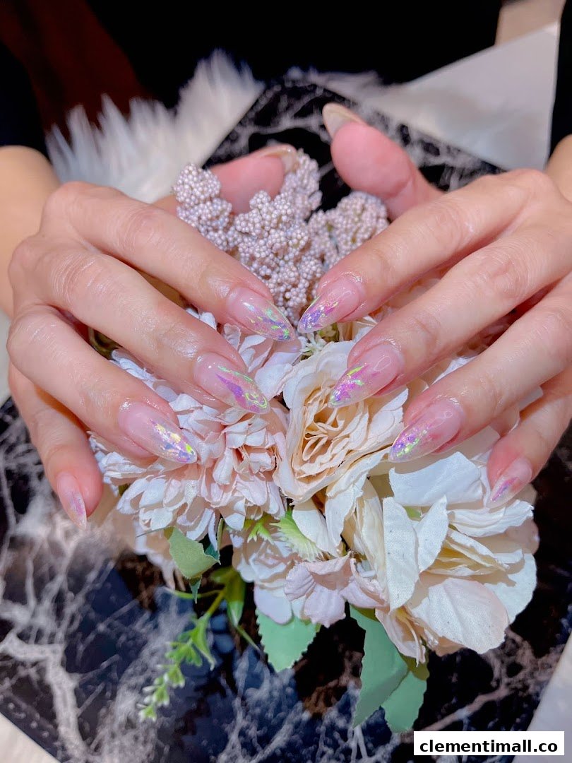 Close-up of hands showcasing elegant, long nails with iridescent glitter accents, holding a bouquet of flowers.