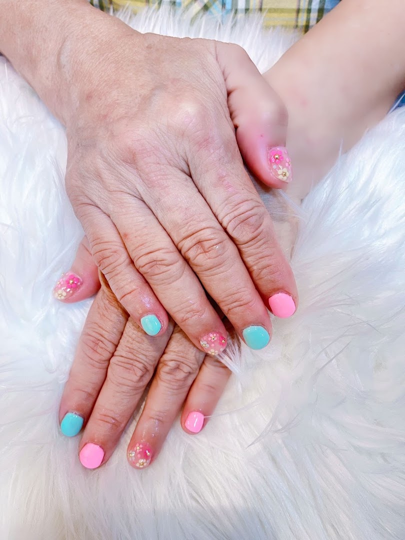 Close-up of hands showcasing vibrant pink and teal nail polish with delicate floral designs.