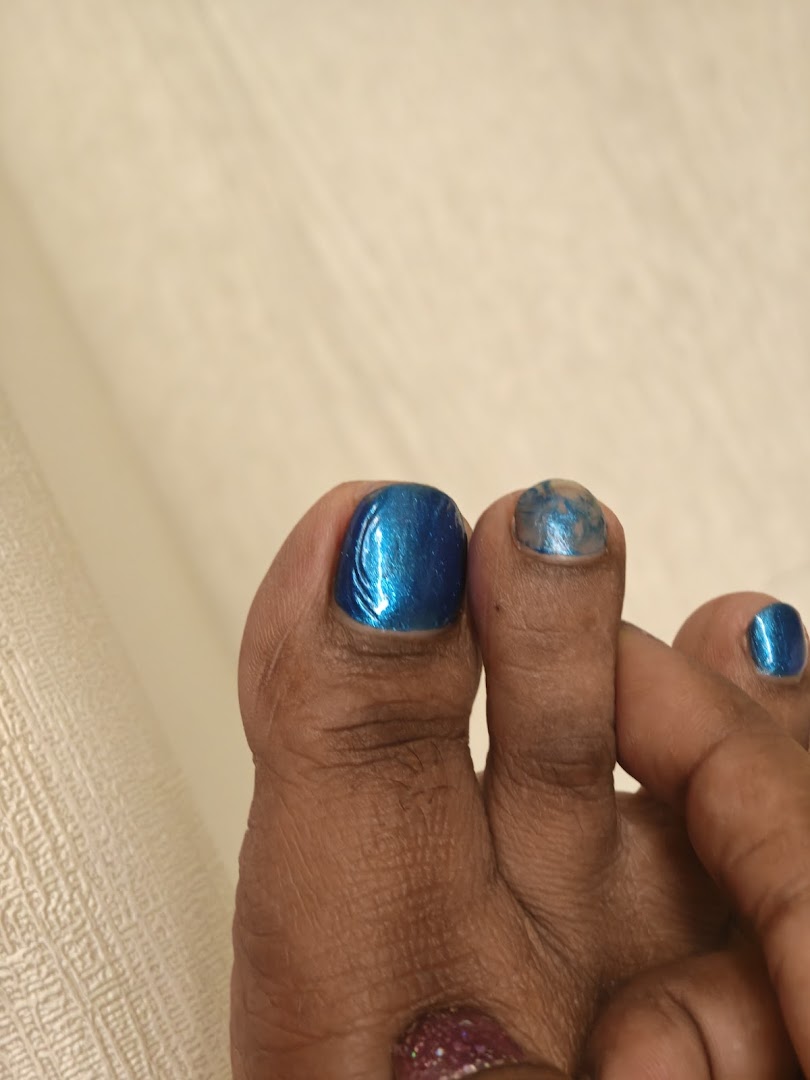 Close-up of a foot with vibrant blue and glitter toenail polish, showcasing a fresh pedicure.