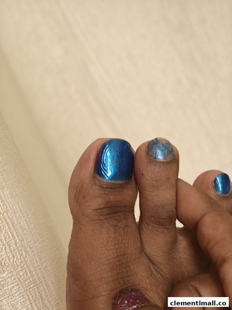 Close-up of a foot with vibrant blue and glitter toenail polish, showcasing a fresh pedicure.