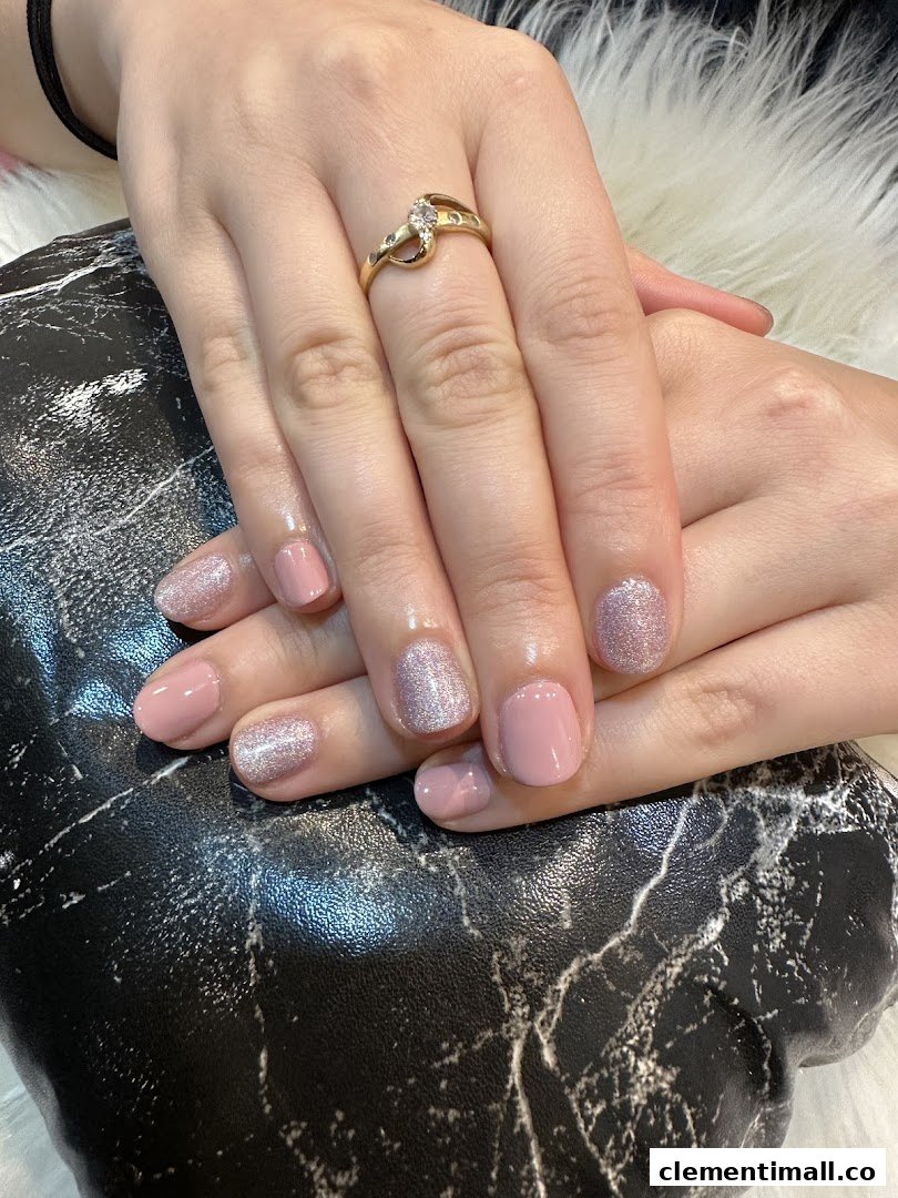 Close-up of hands with a fresh manicure featuring pink and glitter nail polish.