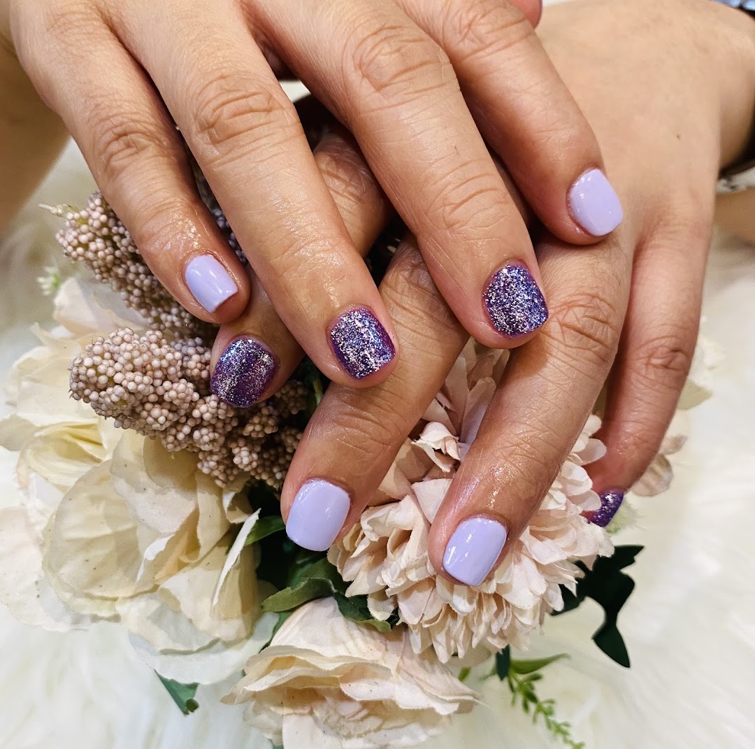 Close-up of hands showcasing a beautiful purple and glitter nail polish design from Nailz Haus.