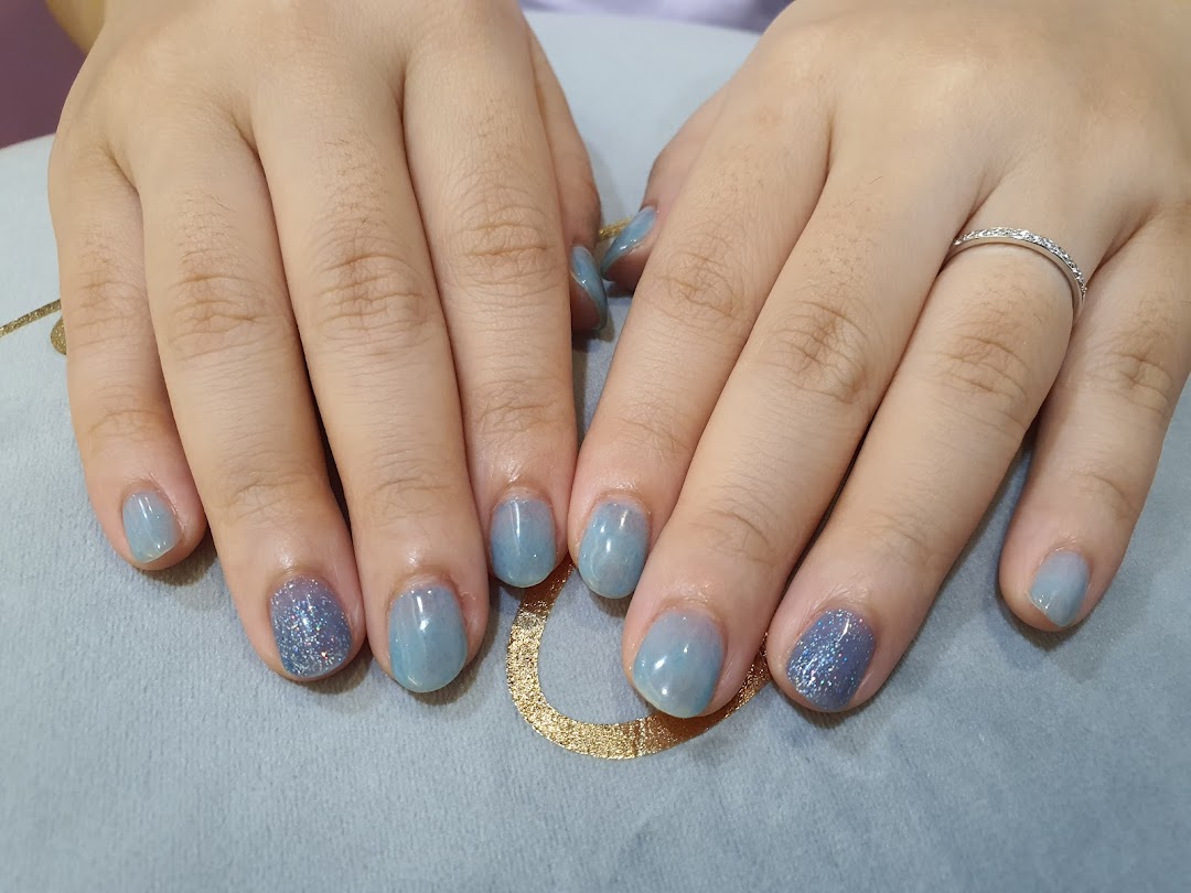 A close-up of hands showcasing a beautiful light blue and glitter nail polish design.
