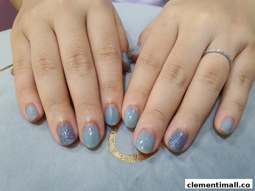 A close-up of hands showcasing a beautiful light blue and glitter nail polish design.