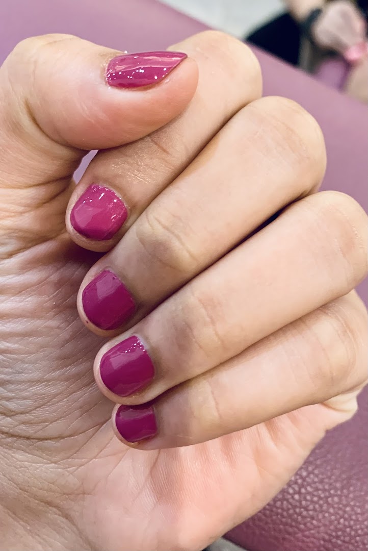 A close-up of a hand showcasing freshly painted magenta nails, highlighting a nail service.