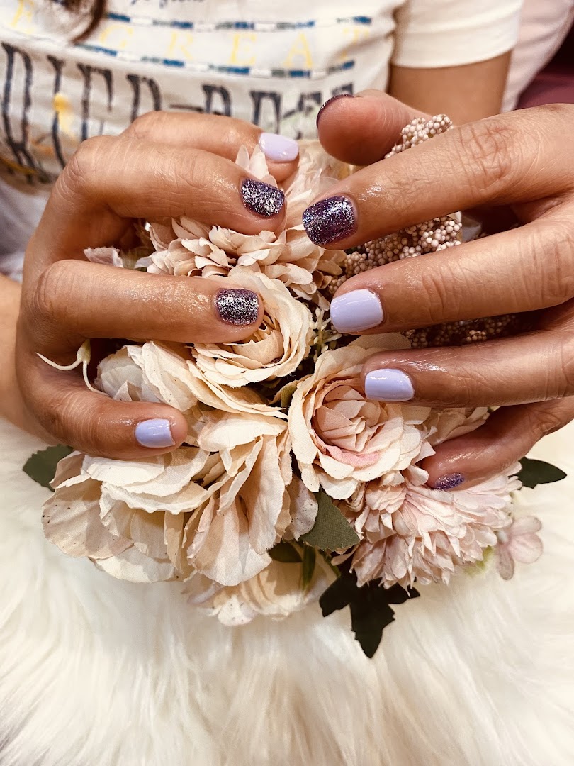 Hands with purple and glitter nail polish holding a bouquet of artificial flowers.