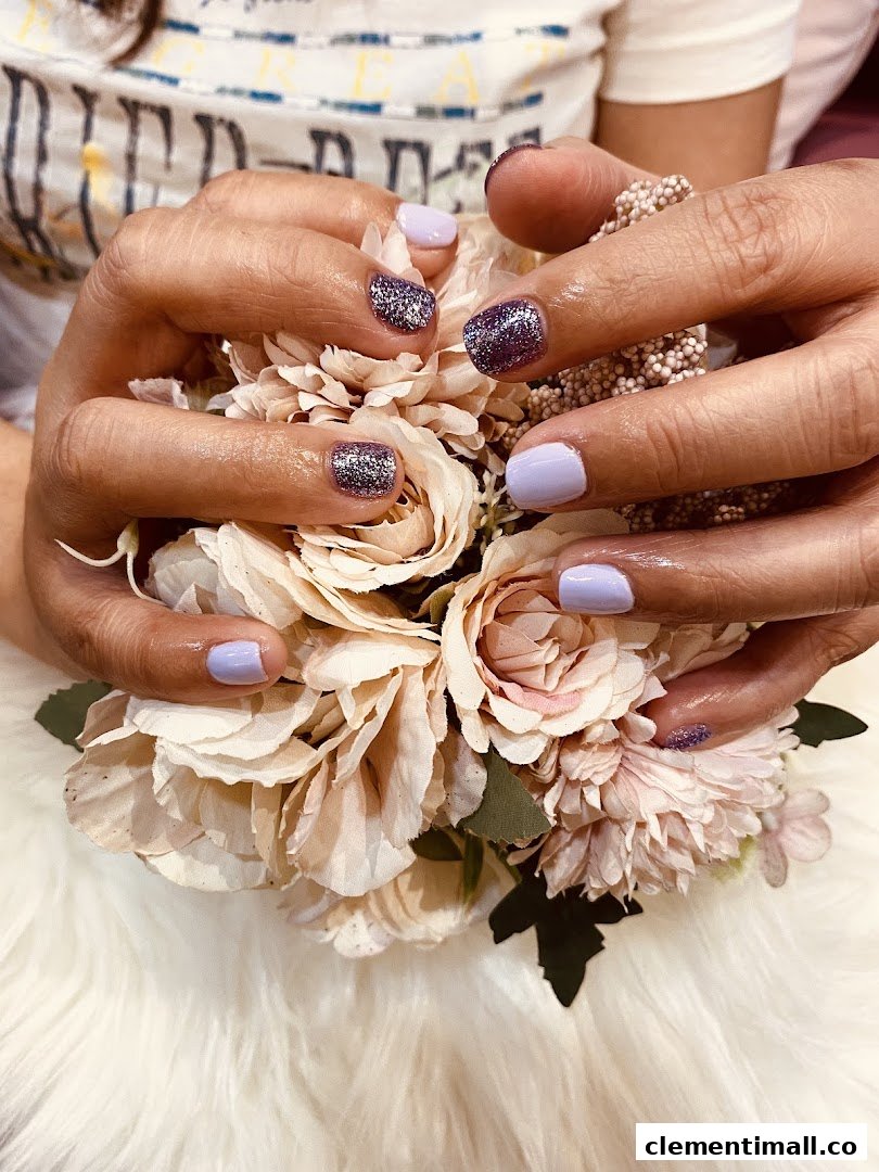 Hands with purple and glitter nail polish holding a bouquet of artificial flowers.