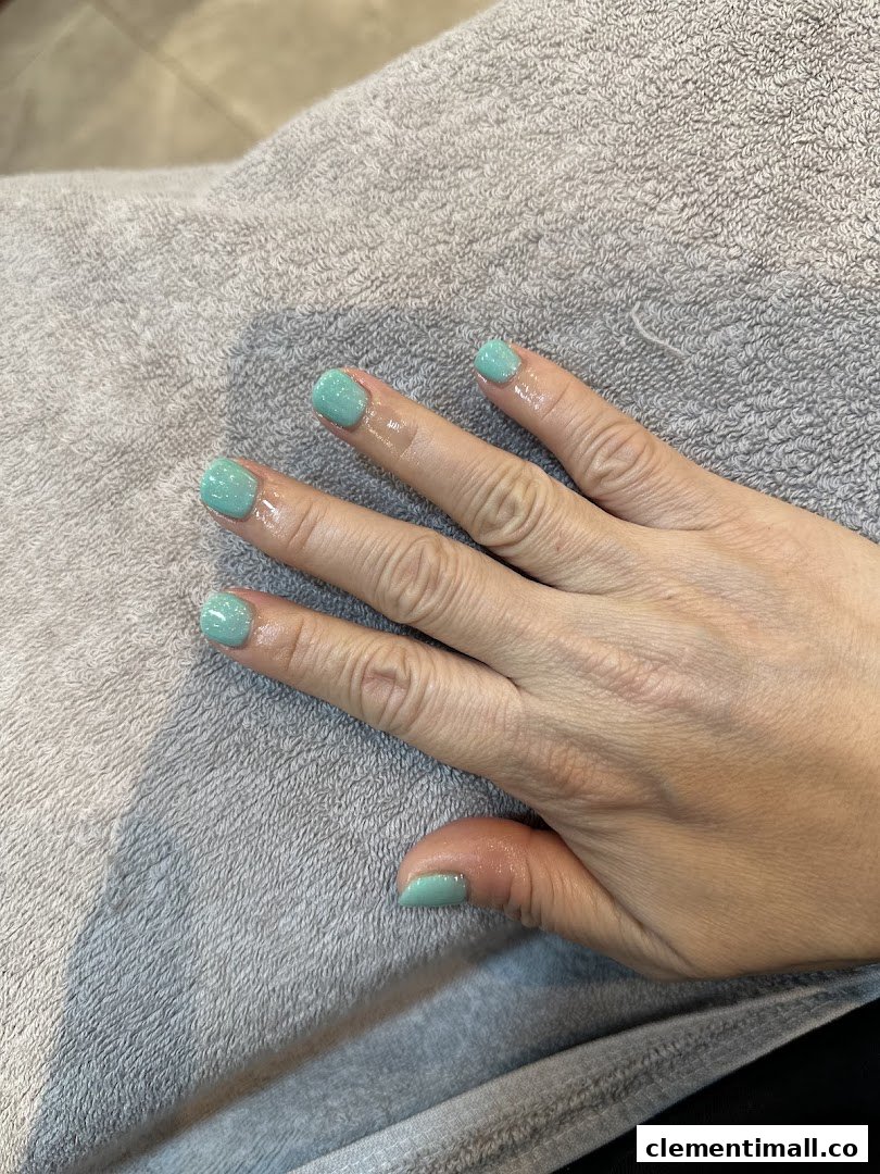A hand with freshly painted light green nails resting on a grey towel, showcasing a manicure.