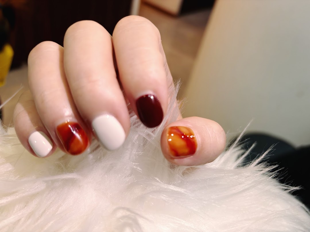 A hand displays beautifully manicured nails with a mix of solid and marbled designs.