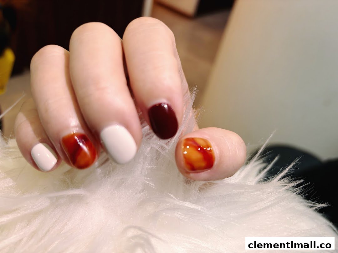 A hand displays beautifully manicured nails with a mix of solid and marbled designs.