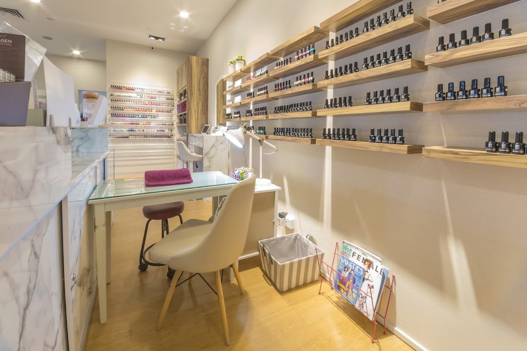 Interior view of a modern nail salon with manicure stations and extensive polish displays.