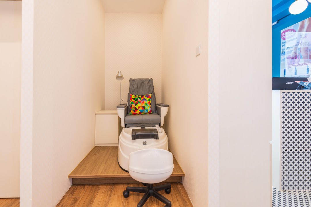 A comfortable pedicure station with a grey chair, foot spa, and colorful cushion.