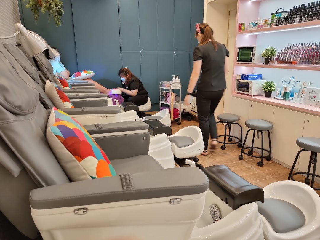 Customers receiving nail treatments in a modern salon with comfortable chairs and product displays.
