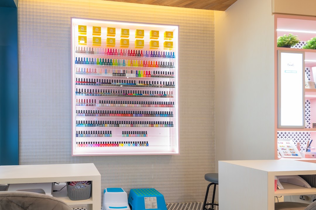 Interior view of a nail salon featuring a large, illuminated display of colorful nail polishes.