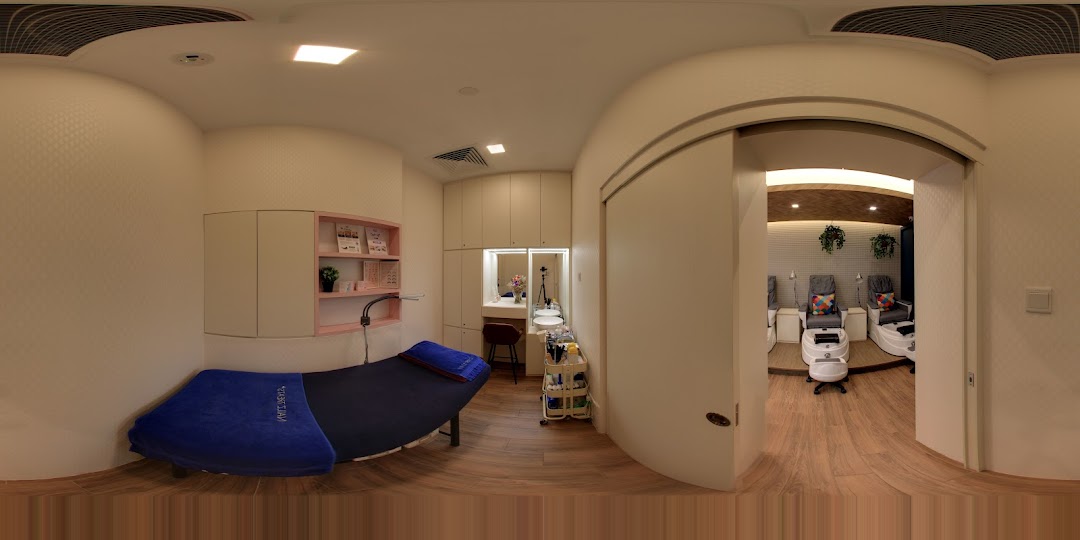 Interior view of a modern nail and beauty salon featuring a treatment bed and pedicure stations.
