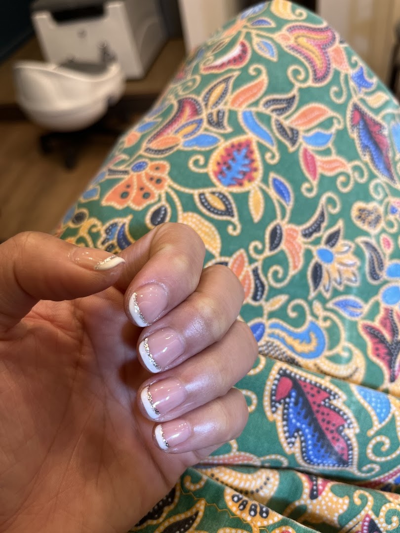 A close-up of a hand showcasing a fresh French manicure with elegant silver glitter accents.