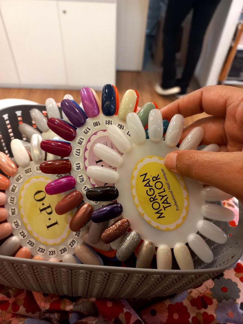 A hand holds a nail polish color swatch wheel featuring OPI and Morgan Taylor shades.