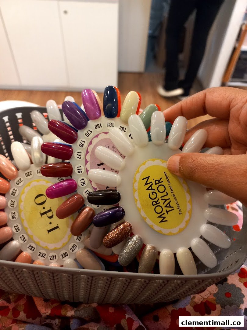 A hand holds a nail polish color swatch wheel featuring OPI and Morgan Taylor shades.