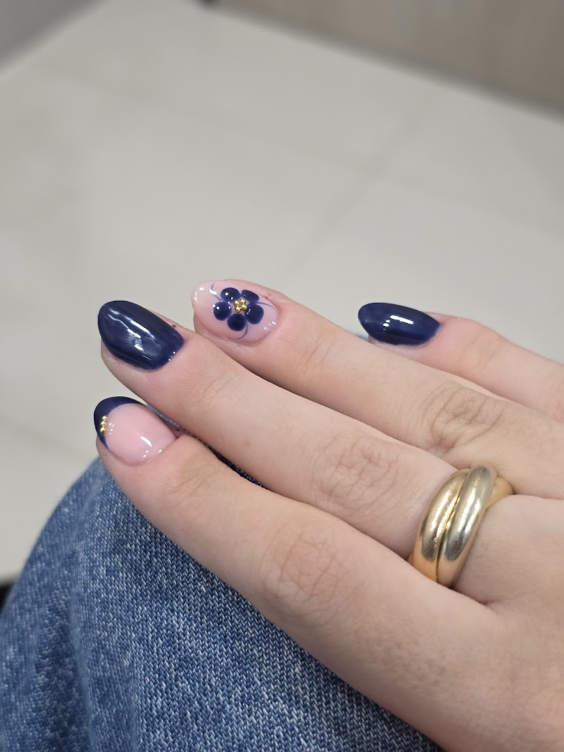 A hand showcasing dark blue and floral nail art designs with gold accents.