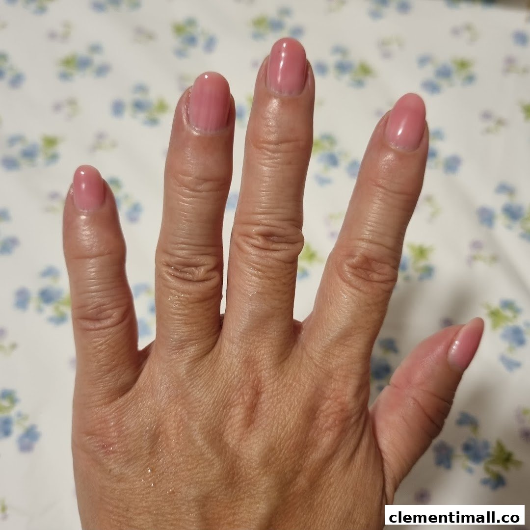 A hand showcasing freshly manicured nails with a soft pink polish against a floral background.