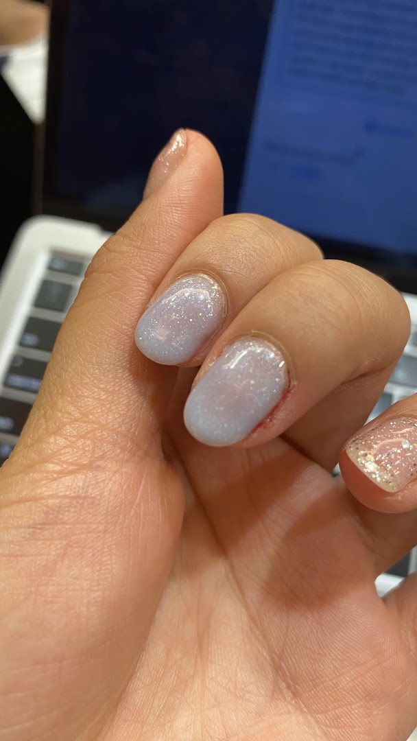 Close-up of a hand showcasing light blue glitter nail polish on several fingers.