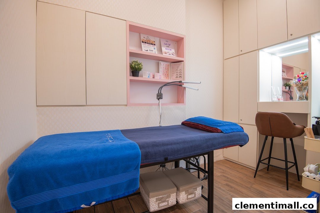 A clean, modern beauty treatment room with a treatment bed, product shelves, and vanity area.