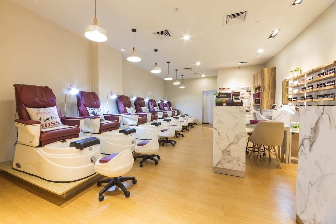 Interior view of a modern nail salon with multiple pedicure chairs and manicure stations.