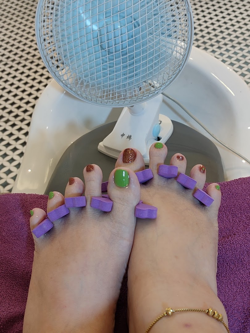 Close-up of feet with freshly painted toenails and toe separators at a nail salon.