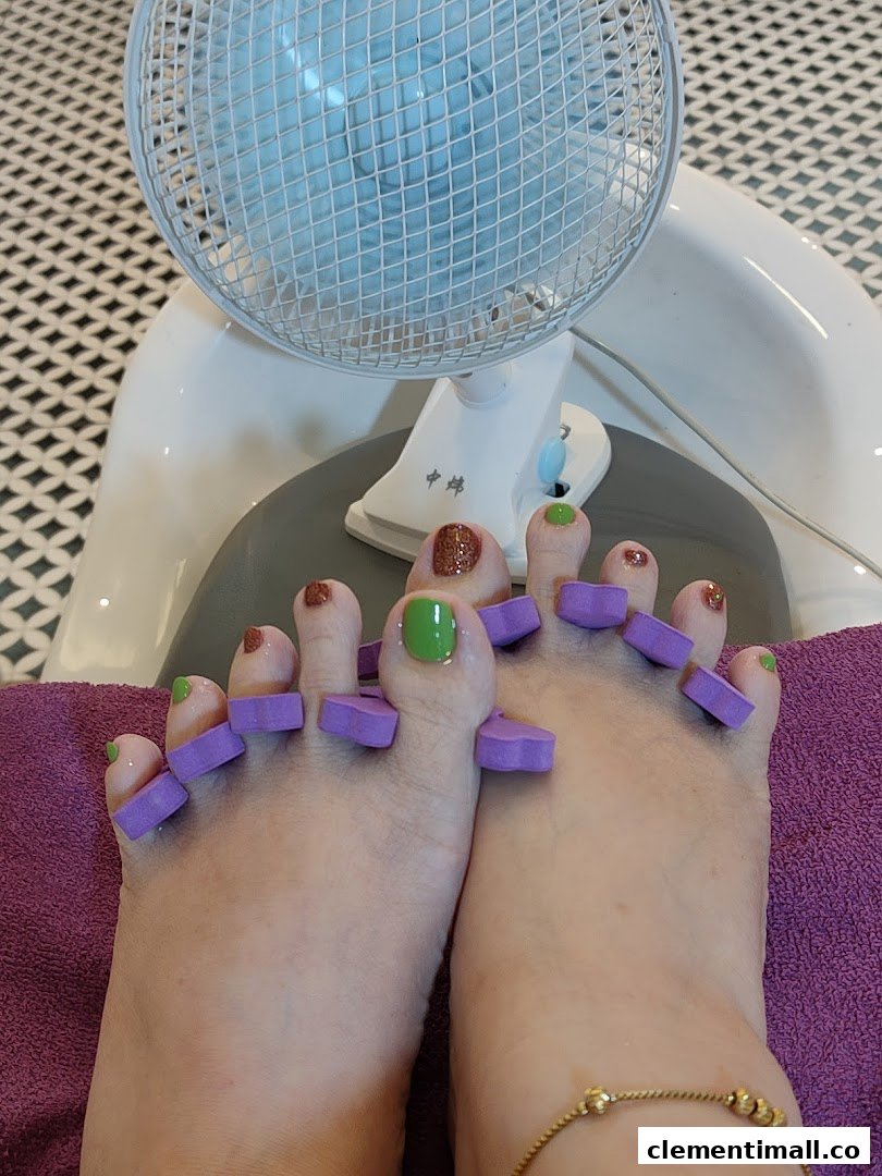 Close-up of feet with freshly painted toenails and toe separators at a nail salon.