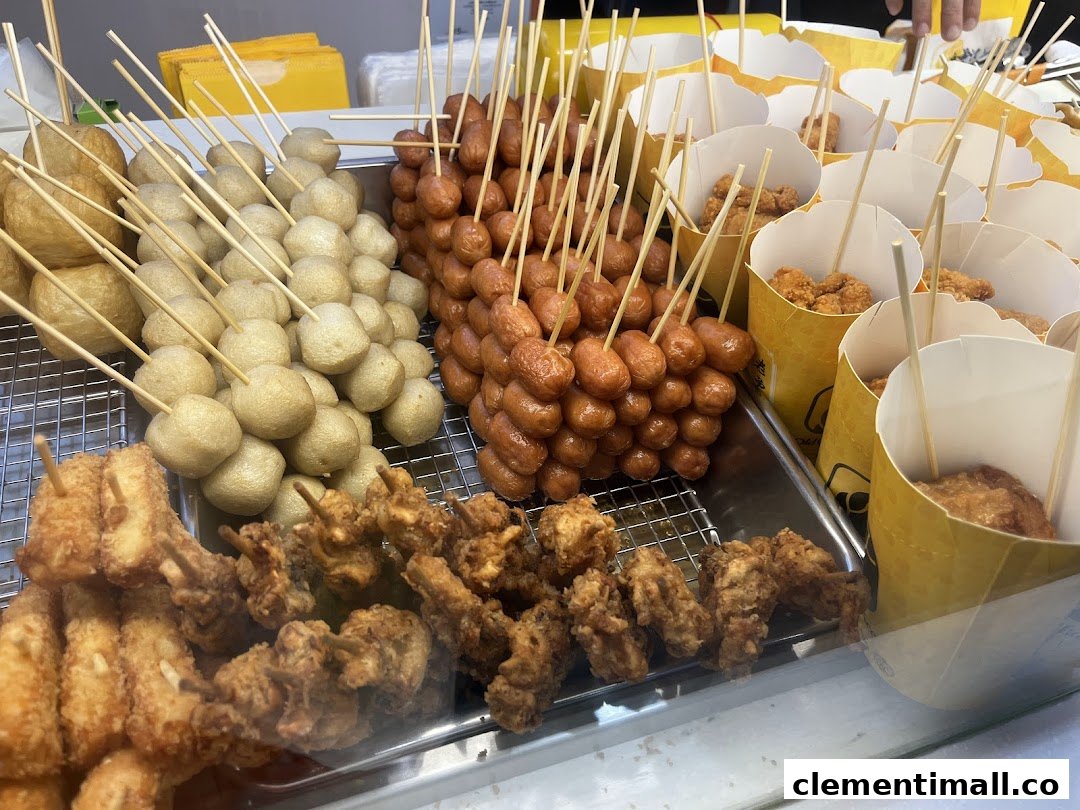 A close-up view of various fried snacks, including fish balls, sausages on skewers, and fried chicken pieces.