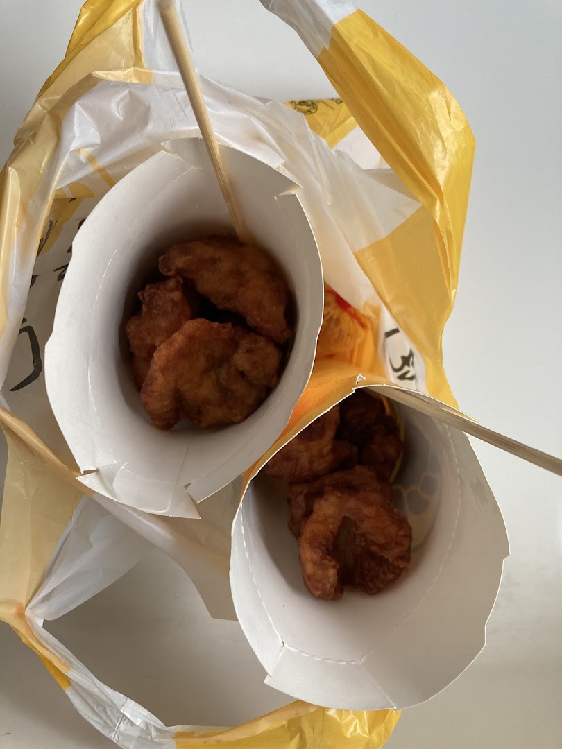 Two cups of golden-fried snacks from Old Chang Kee, ready for takeaway in a yellow bag.