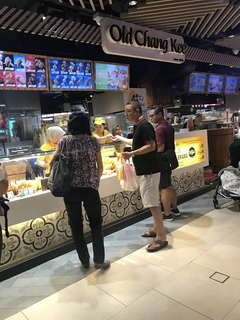 Customers at Old Chang Kee counter, featuring digital displays of fried snacks and a bustling atmosphere.