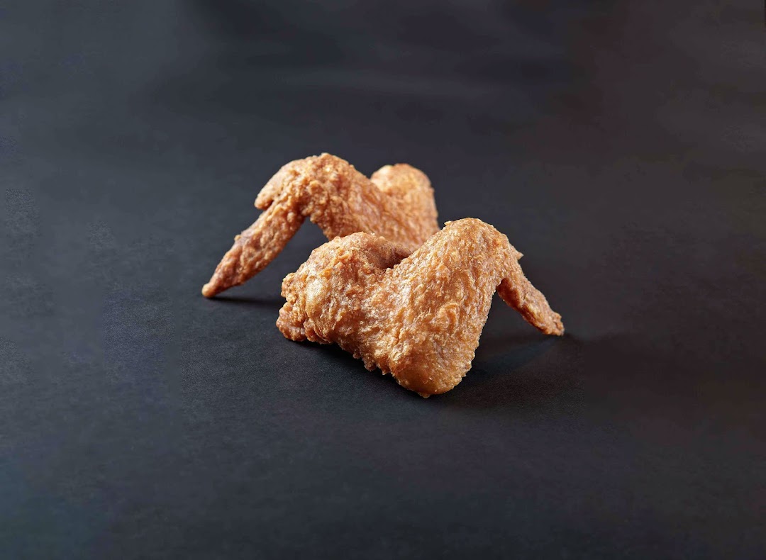 Two golden-brown fried chicken wings are presented on a dark, plain background.