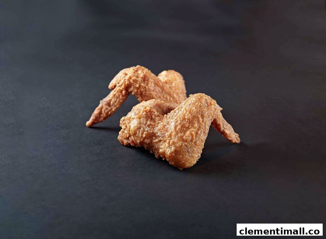 Two golden-brown fried chicken wings are presented on a dark, plain background.
