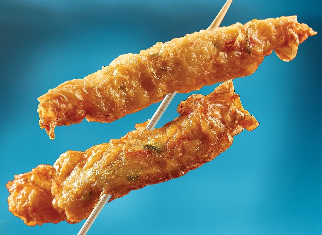 Two golden-fried snacks on skewers, showcasing their crispy texture against a blue background.