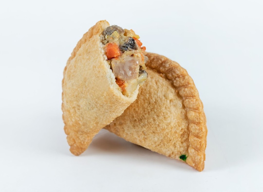A golden-brown curry puff, with one piece cut open to reveal its savory filling of meat and vegetables.