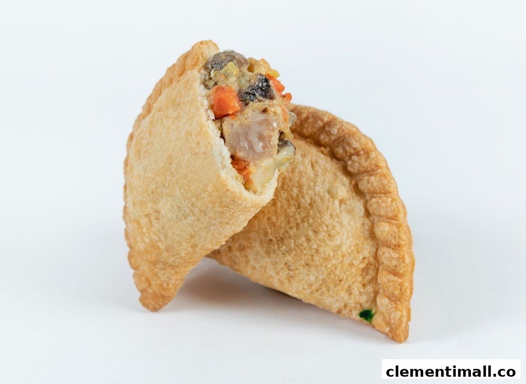 A golden-brown curry puff, with one piece cut open to reveal its savory filling of meat and vegetables.