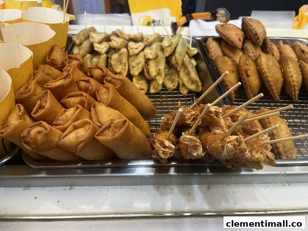 A vibrant display of golden-fried snacks including spring rolls, curry puffs, and other fried items.