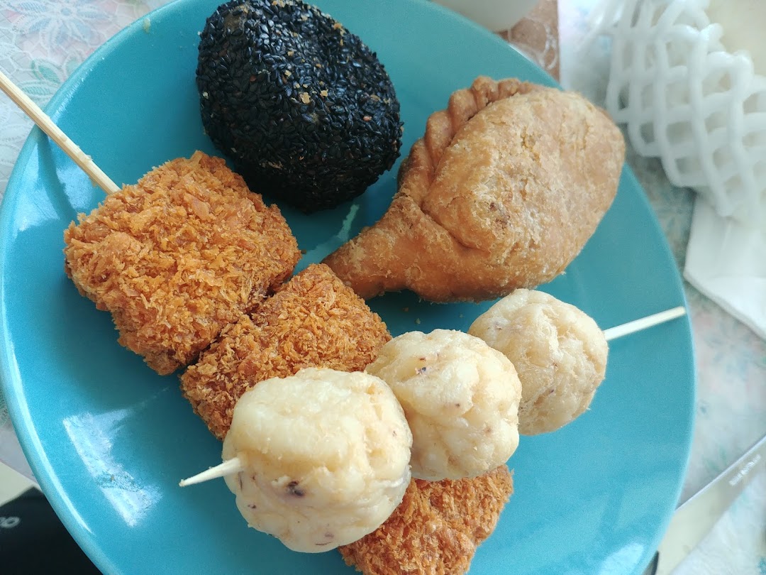 A vibrant blue plate showcasing a variety of Old Chang Kee's popular fried snacks, including curry puffs and fish balls.