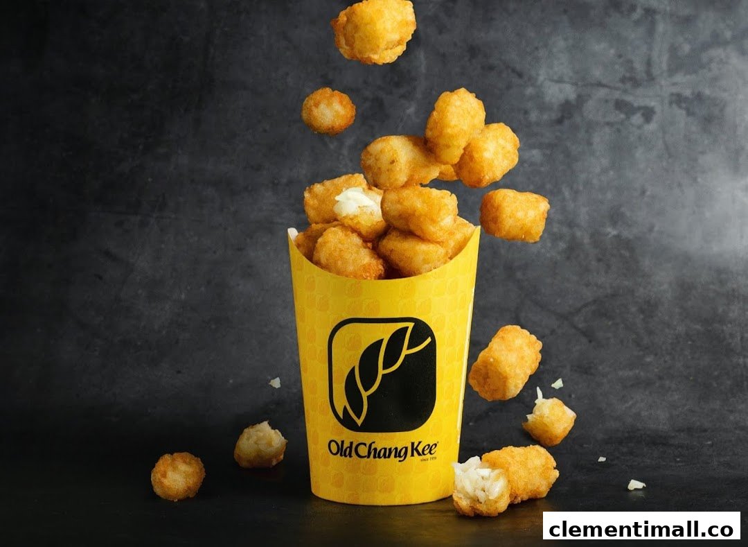 A yellow Old Chang Kee cup filled with golden, crispy tater tots against a dark background.