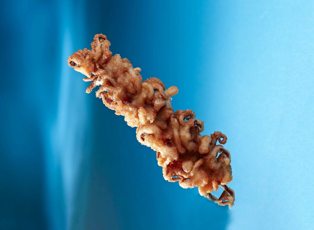 A close-up of golden-brown fried calamari or squid tentacles against a vibrant blue background.
