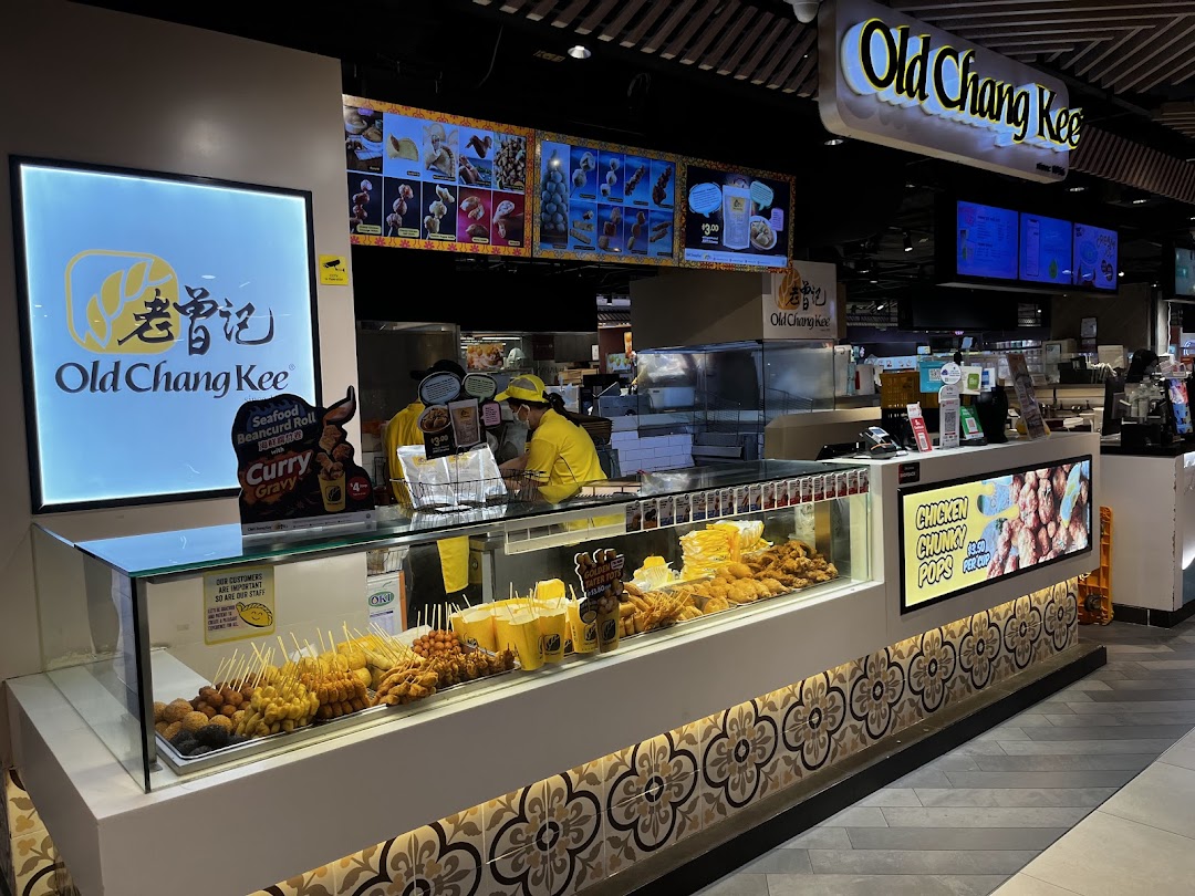 Interior view of Old Chang Kee showcasing a vibrant display of fried snacks and a busy service counter.