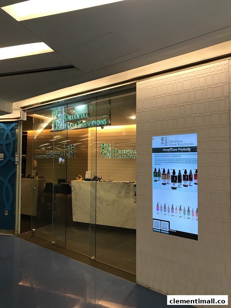 The illuminated glass entrance of Oriental Hair Solutions, featuring a digital display showcasing home-care products.