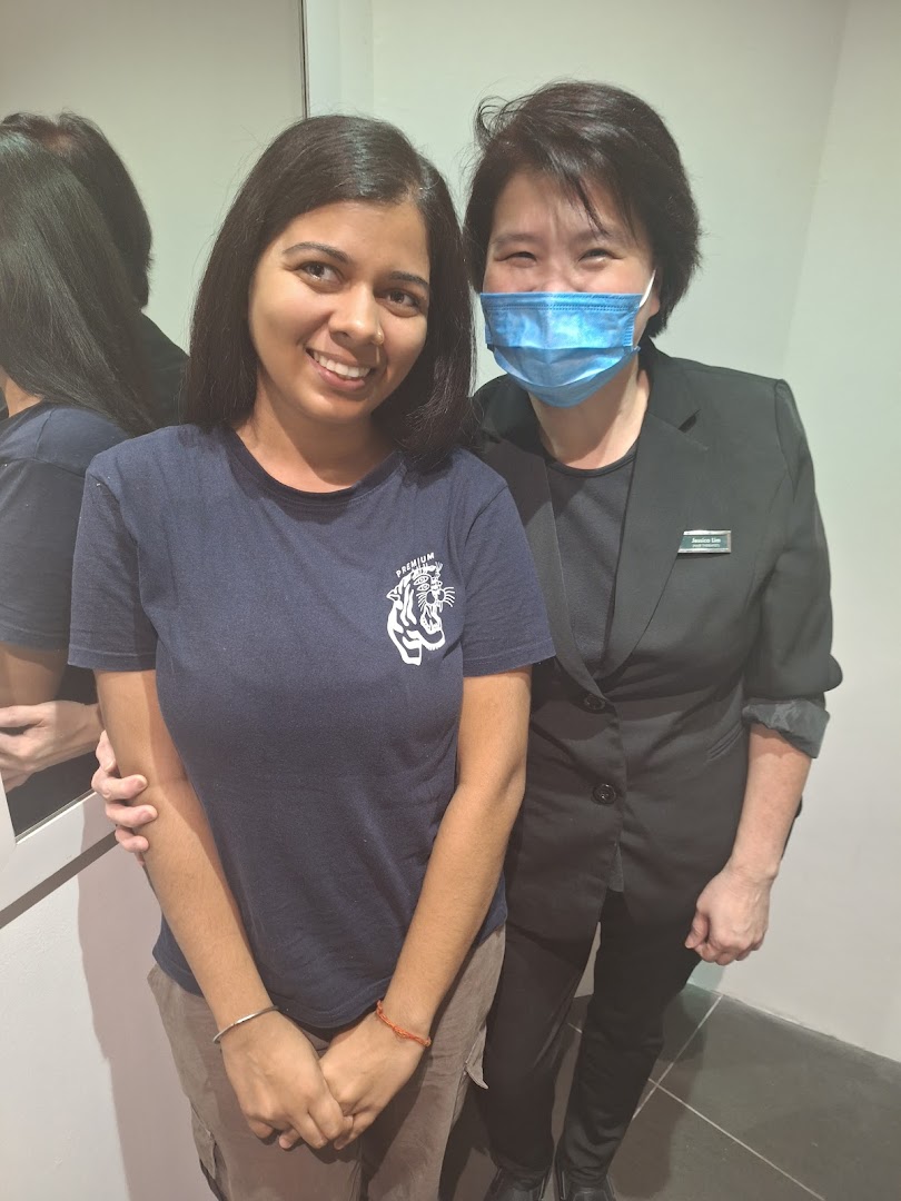 Two women, one smiling and one masked, posing together inside Oriental Hair Solutions.