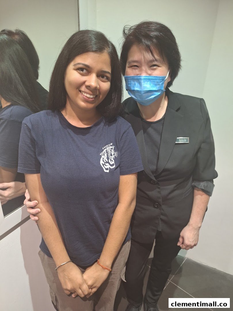 Two women, one smiling and one masked, posing together inside Oriental Hair Solutions.
